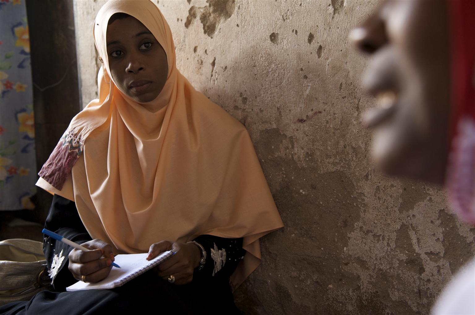 A social worker takes notes while she speaks to a beneficiary